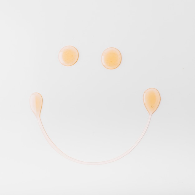 Smiley face made with honey on white background