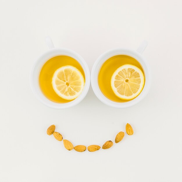 Smiley face made with lemon tea cup and almonds isolated on white background