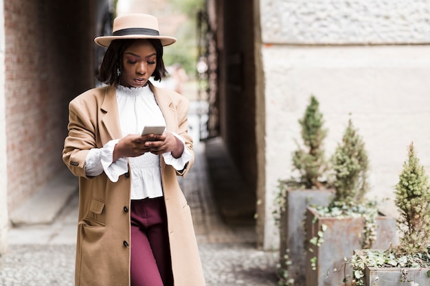 Smiley fashionable woman looking on her phone with copy space