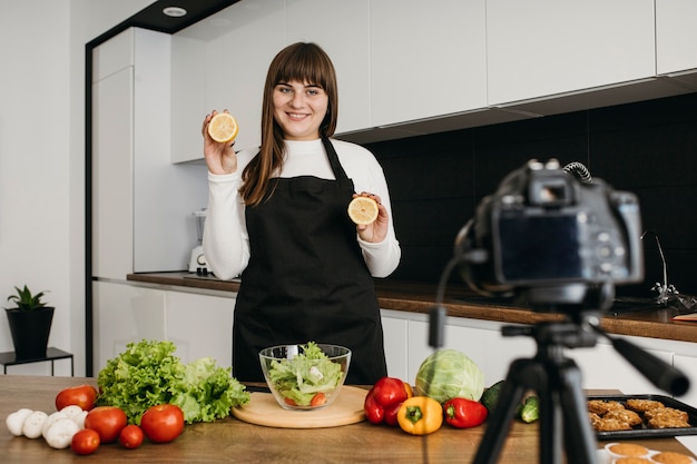 Free photo smiley female blogger recording herself while preparing salad