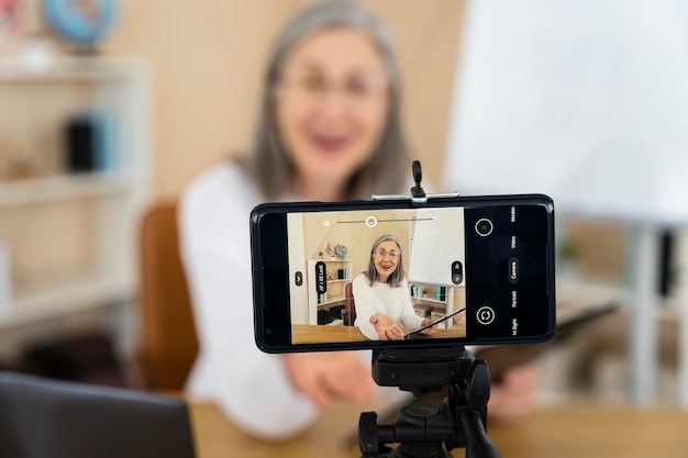 Smiley female english teacher doing online lessons on her smartphone