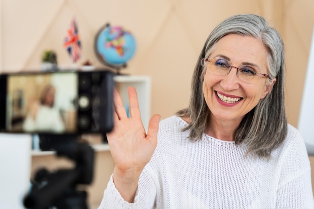 Smiley female english teacher doing online lessons on her smartphone