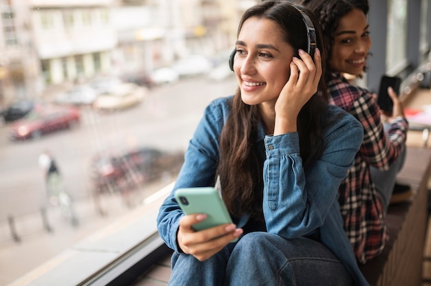 Free photo smiley female friends listening to music on headphones