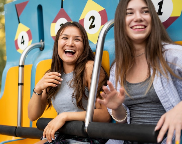 Free Photo smiley female friends on the ride at amusement park