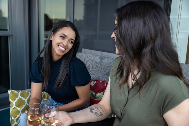 Smiley female friends spending time together and drinking wine at a terrace