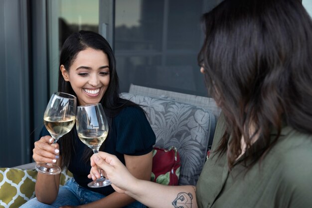 Smiley female friends spending time together and drinking wine at a terrace