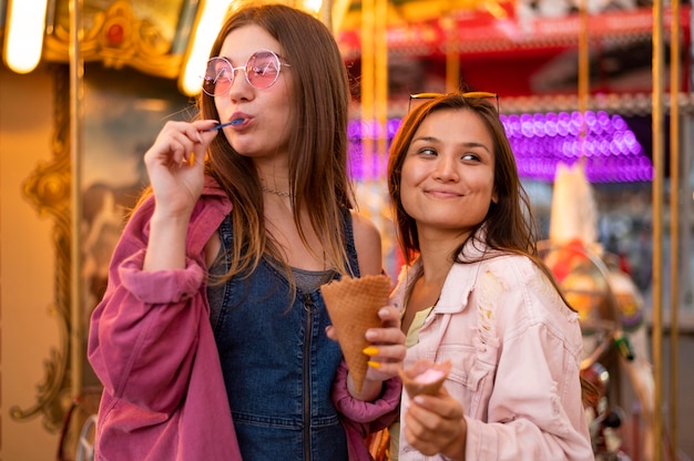 Smiley female friends with sunglasses at the amusement park