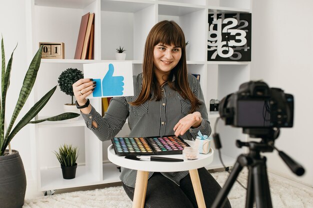 Smiley female make-up blogger with streaming at home with camera