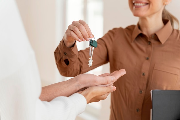 Free photo smiley female realtor handing couple the keys for their new home