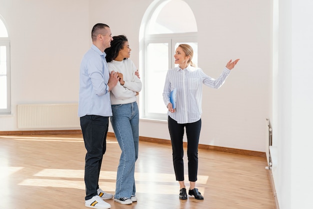 Smiley female realtor showing empty house to couple