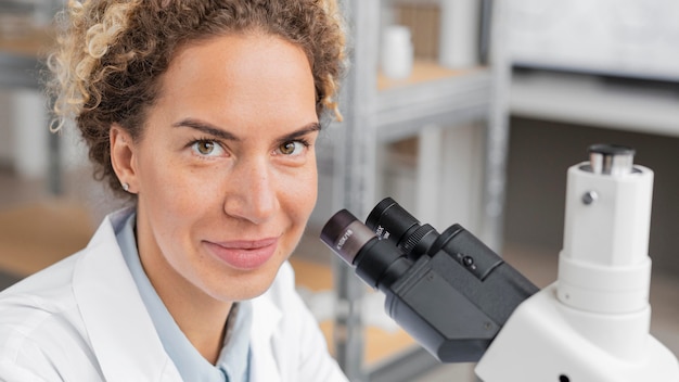 Free Photo smiley female researcher in the laboratory using microscope