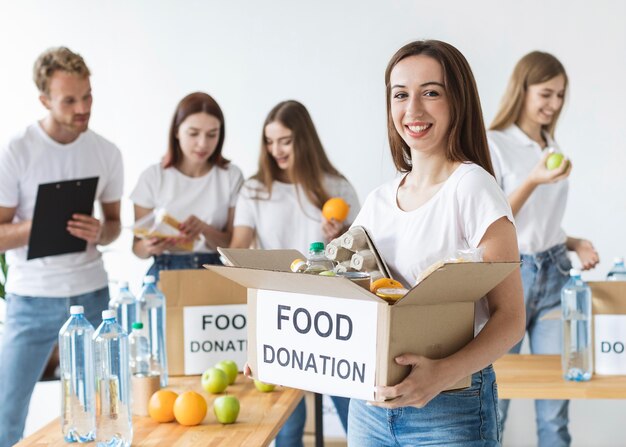 Smiley female volunteer holding box with food donations