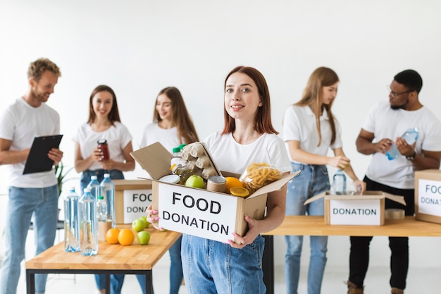 Free photo smiley female volunteer holding donation box with food