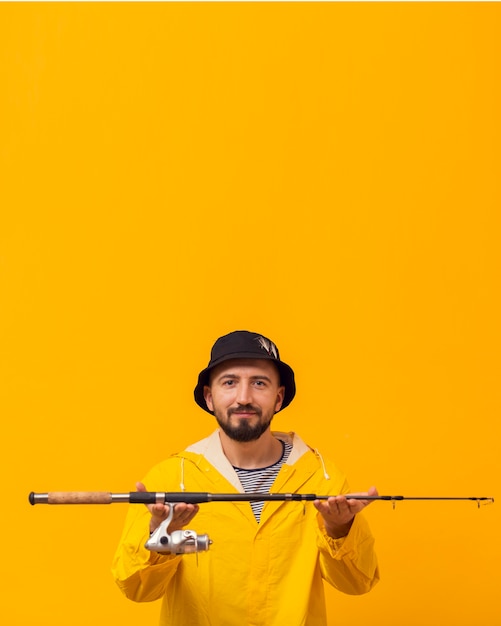 Free Photo smiley fisherman holding up fishing rod with copy space