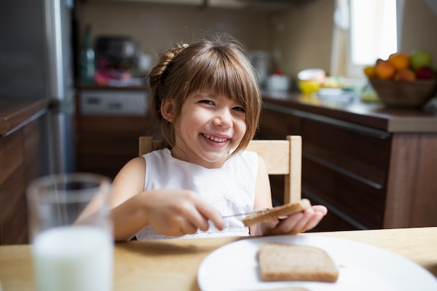 Smiley girl eating breakfast at home