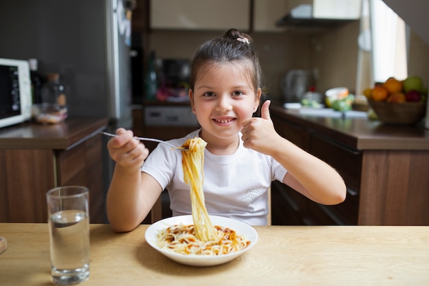 Smiley girl having pasta at lunch