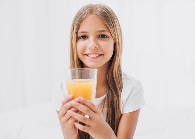 Smiley girl holding a glass of orange juice