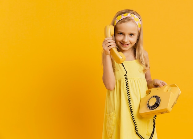 Free photo smiley girl holding telephone with copy space