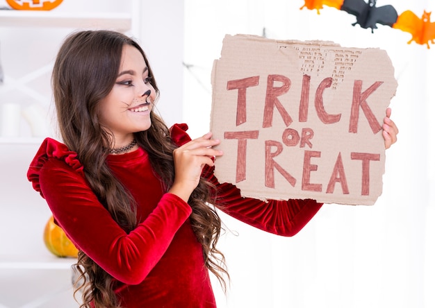 Free Photo smiley girl holding trick or treat sign