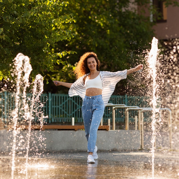 Free Photo smiley girl posing surrounded by fountain