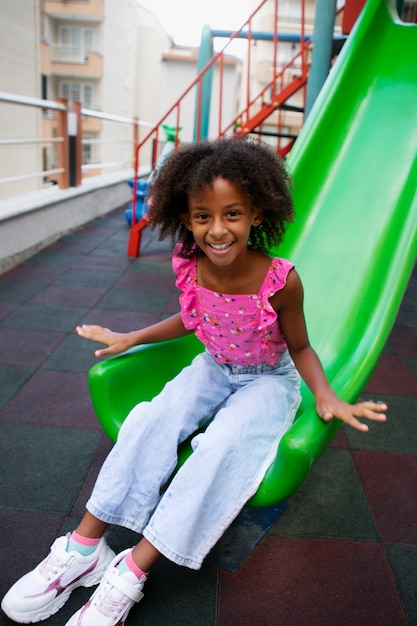 Smiley girl on slide full shot