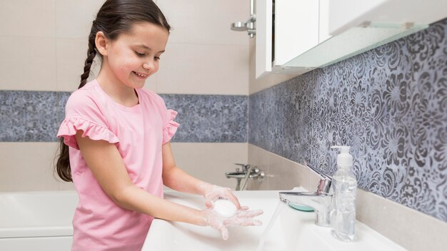 Smiley girl washing her hands side view