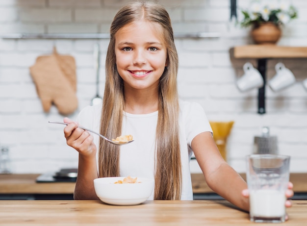 Smiley girl with bowl of cereal looking at the camera 