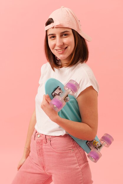 Smiley girl with cap holding skateboard