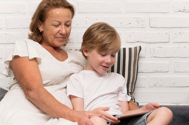 Smiley grandmother and kid with tablet