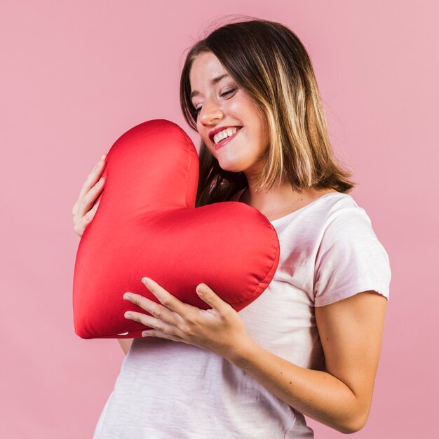 Smiley holding a heart shaped pillow