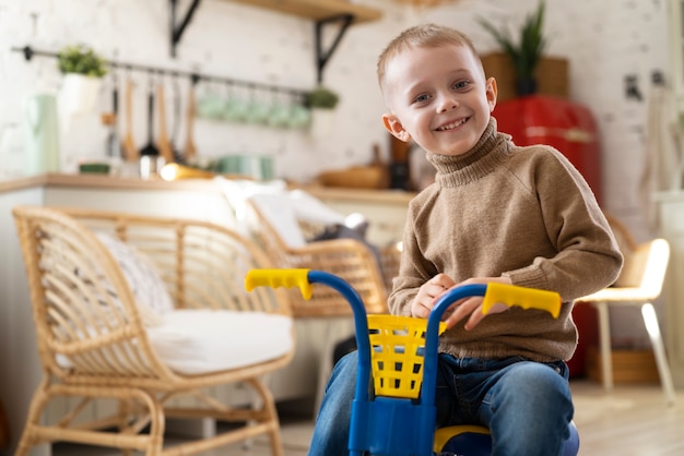 Smiley kid with tricycle indoors medium shot