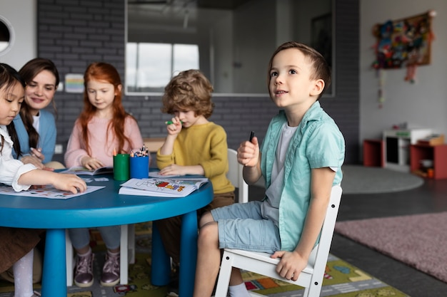 Smiley kids sitting together at table side view