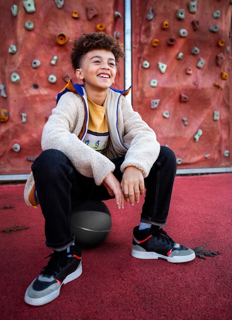 Smiley little boy posing next to a climbing wall