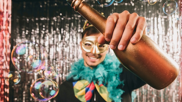 Smiley male at carnival party with champagne bottle