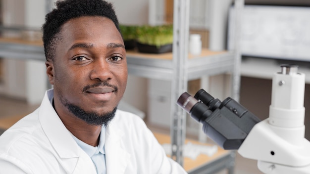 Smiley male researcher in the laboratory using microscope