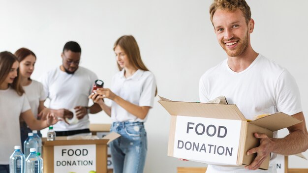 Smiley male volunteer holding food donations box