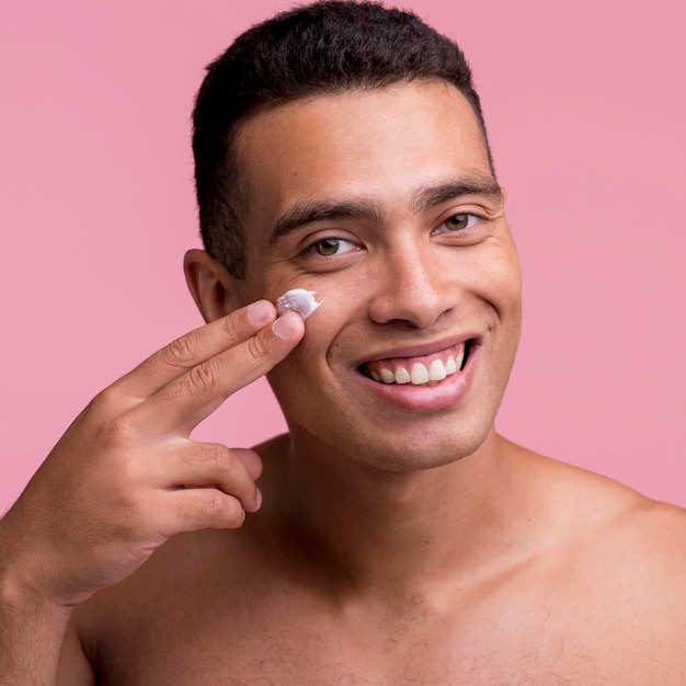 Smiley man applying cream on his face