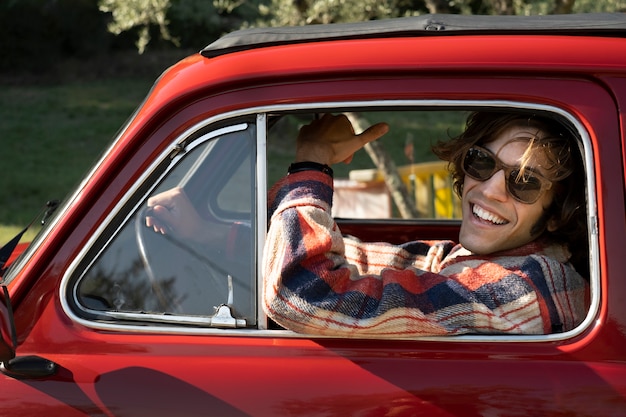 Smiley man driving red car close up