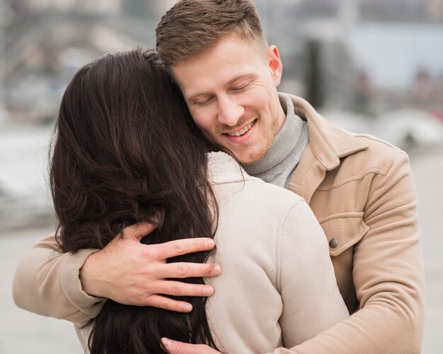 Smiley man holding woman outdoors