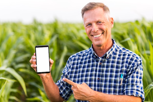 Free photo smiley man indicating at the phone mock-up