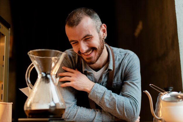 Smiley man posing in apron with coffee pot