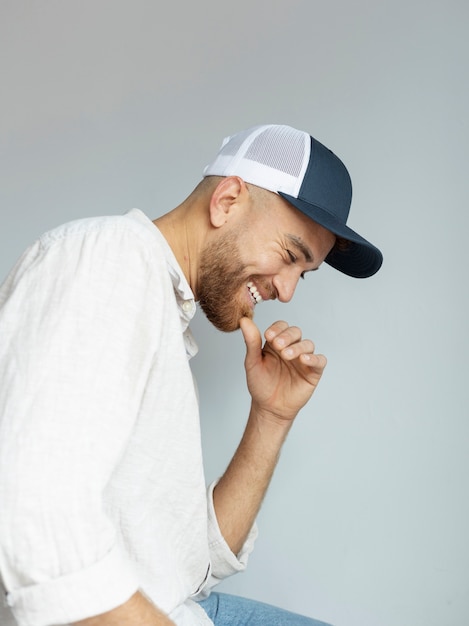 Free photo smiley man posing with trucker hat side view