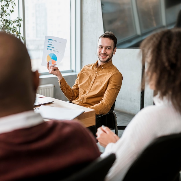 Smiley man presenting something to his colleagues during a meeting