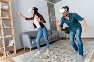 Free photo smiley man and woman having fun at home with virtual reality headset