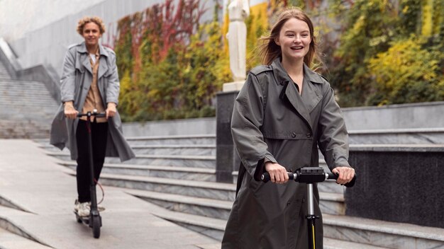 Smiley man and woman using electric scooter outdoors