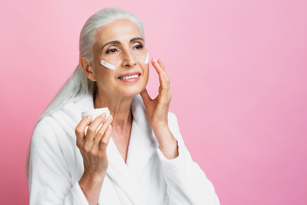 Smiley mature woman applying skin care