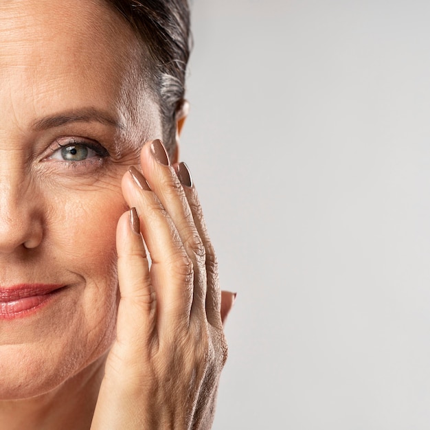 Smiley mature woman with make-up on posing with hand on face