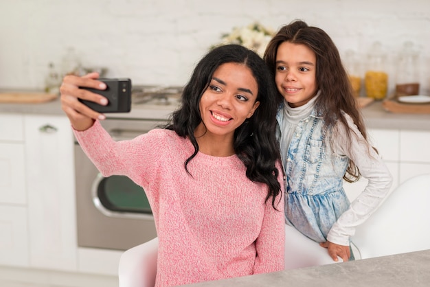 Free photo smiley mom and daughter taking photos