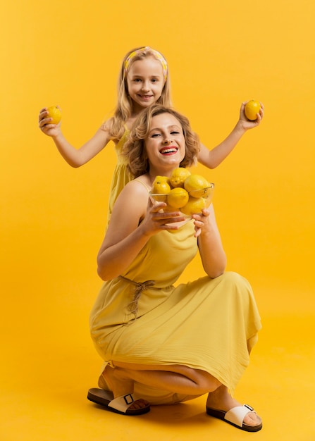 Smiley mother and daughter holding lemons