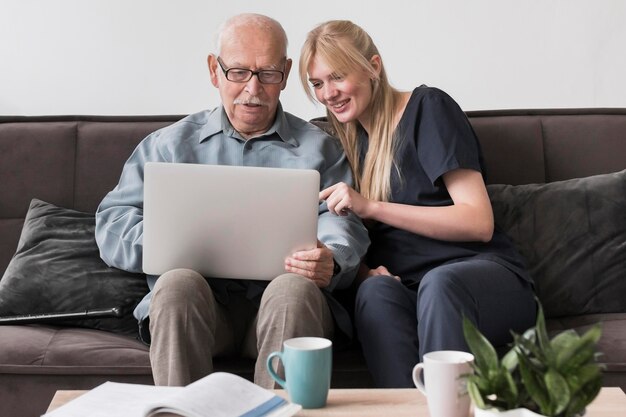 Smiley nurse showing old man the laptop